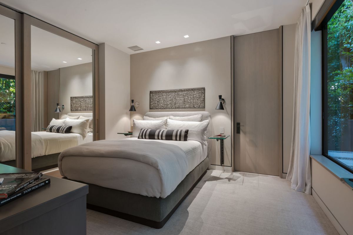 Bold, lighter accents may make a room feel much brighter if subdued walls look a little… drab. As seen in this space, accents like white drapes, nightstands, and hotel-style bedding contribute to the ambiance's coziness.