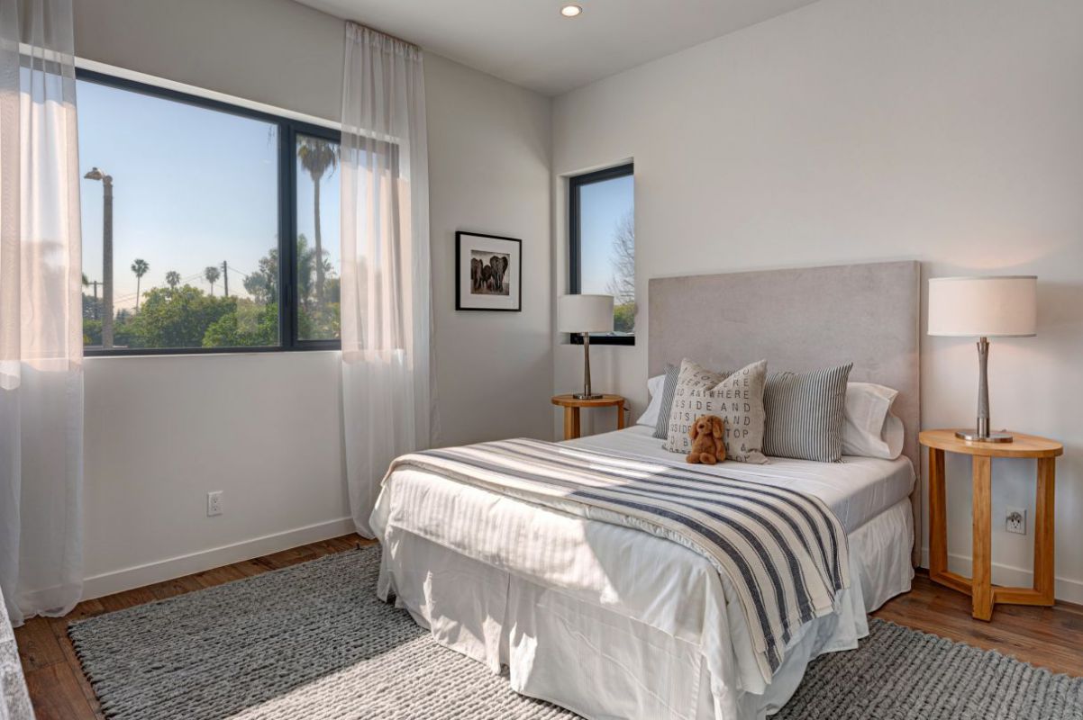 In order to create a contemporary setting that feels both cozy and stylish, modern farmhouse design gives rustic accents a modern makeover. White paint was used to enhance the wood paneled walls. Cozy feelings are evoked by a gorgeous headboard and decorative pillows.