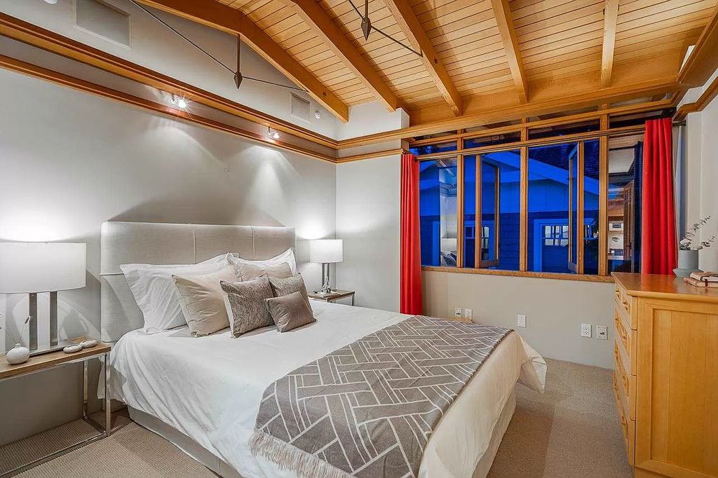 This minimalist bedroom's gray walls are gently textured in addition to being exquisitely subdued. The wooden inlays and trim provide a welcome bit of warmth, and the paint finish gives the attic space's elegant architectural features dimension.
