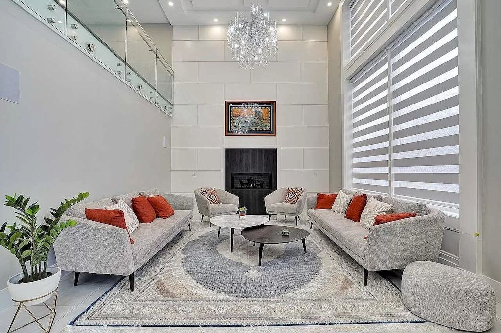 The living room is decorated with simple white walls, silver furniture, brick walls, orange pillows, and minimalist coffee tables. In the living room, orange is used to create contrast and neutrality with cool tones. This detail alone increased the room's warmth.