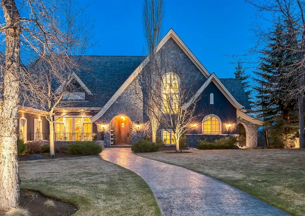 The Magnificent Home in Alberta features extensive hand-hewn grey Canmore limestone, soaring peaks, arched windows, and a majestic sloped roof now available for sale