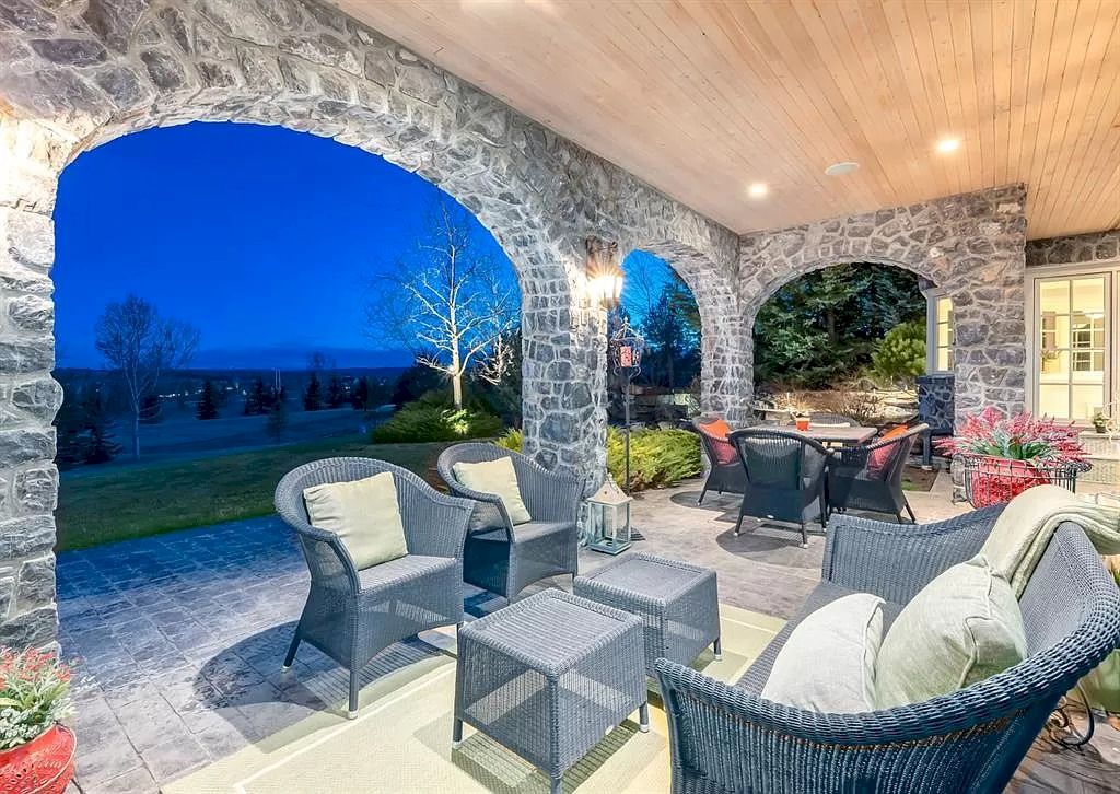 The Magnificent Home in Alberta features extensive hand-hewn grey Canmore limestone, soaring peaks, arched windows, and a majestic sloped roof now available for sale