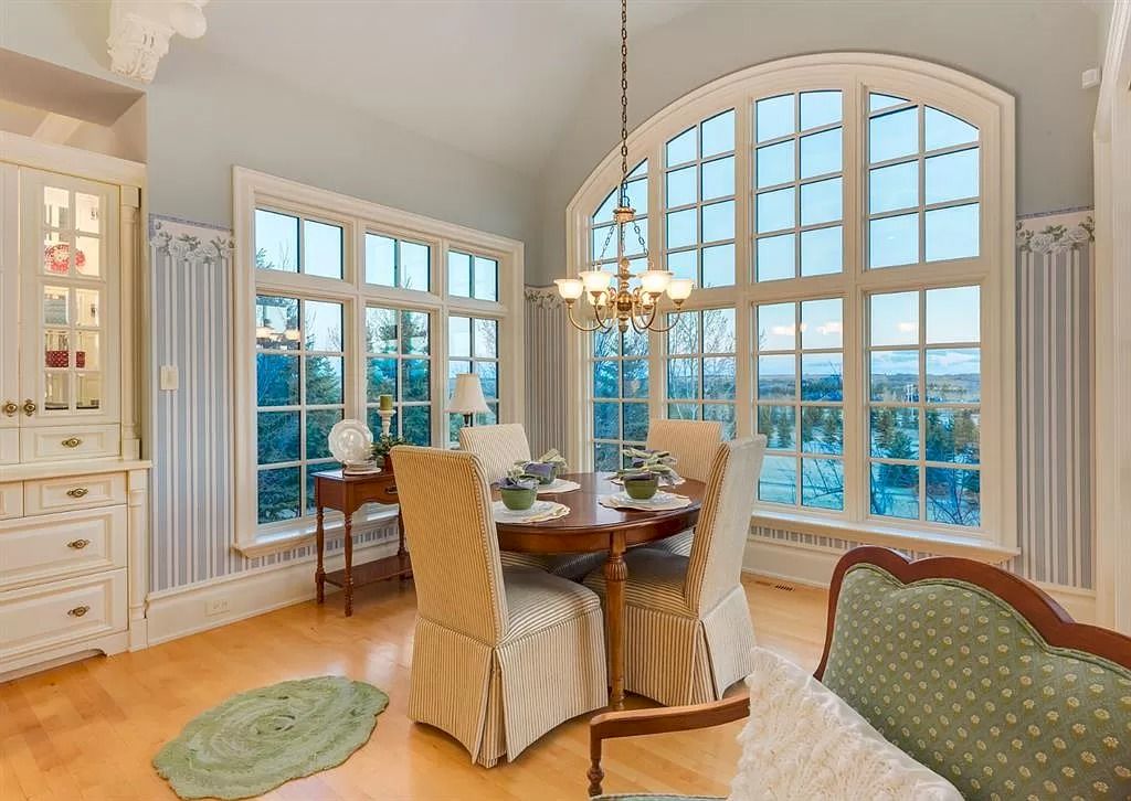 The Magnificent Home in Alberta features extensive hand-hewn grey Canmore limestone, soaring peaks, arched windows, and a majestic sloped roof now available for sale