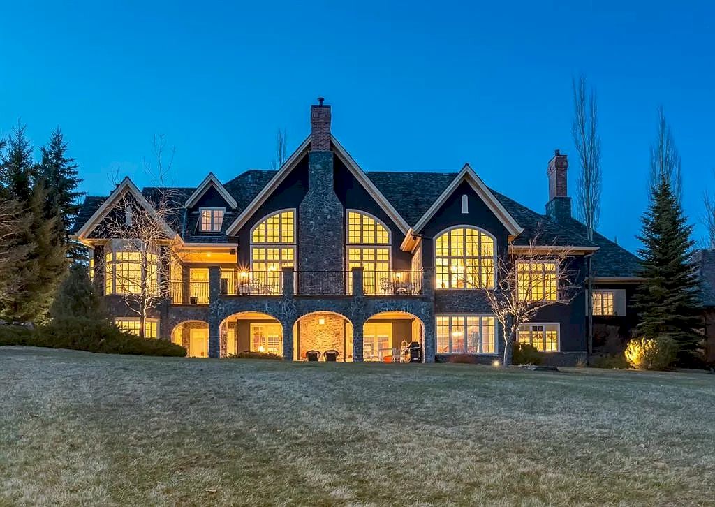 The Magnificent Home in Alberta features extensive hand-hewn grey Canmore limestone, soaring peaks, arched windows, and a majestic sloped roof now available for sale