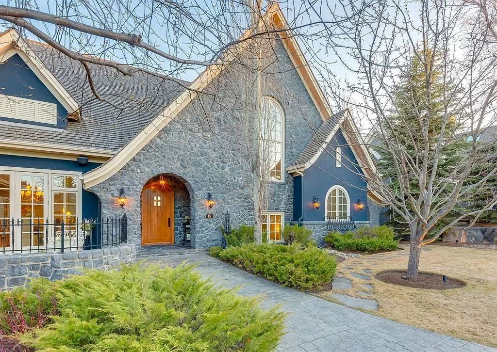 The Magnificent Home in Alberta features extensive hand-hewn grey Canmore limestone, soaring peaks, arched windows, and a majestic sloped roof now available for sale