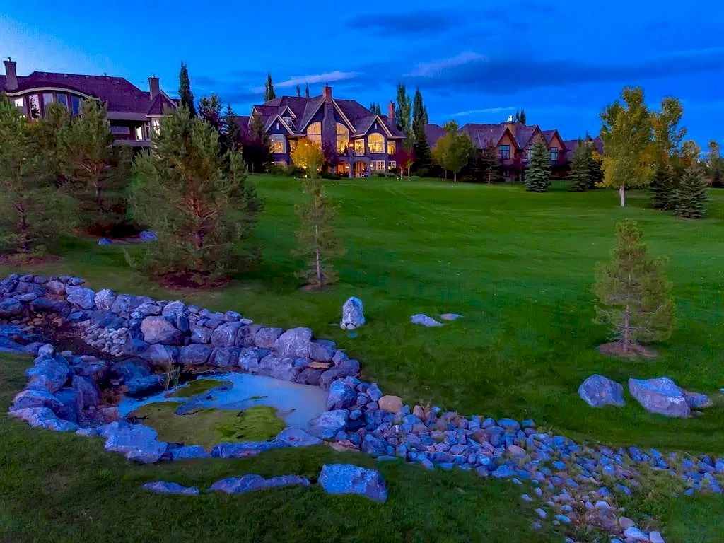 The Magnificent Home in Alberta features extensive hand-hewn grey Canmore limestone, soaring peaks, arched windows, and a majestic sloped roof now available for sale