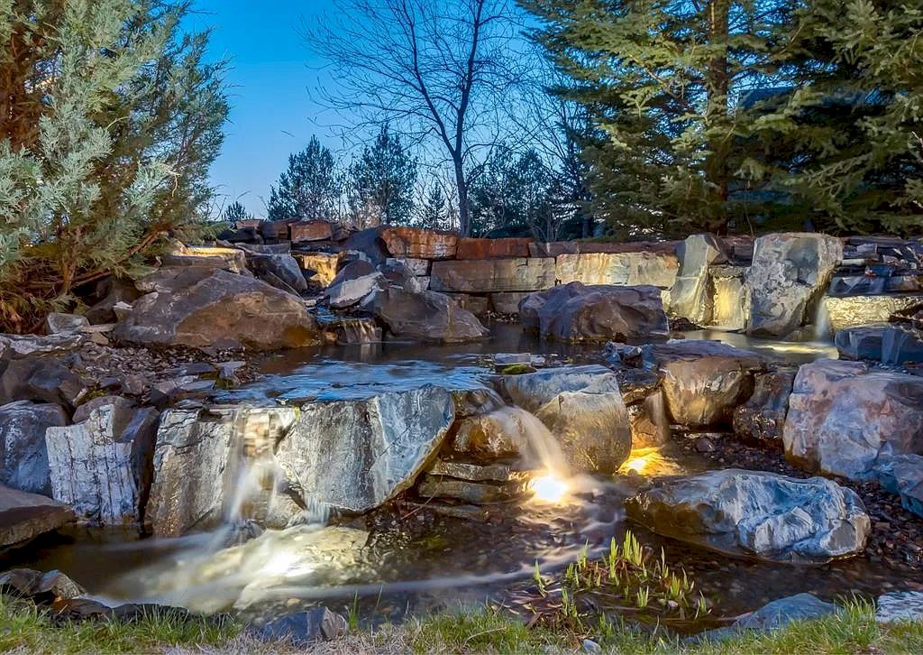 The Magnificent Home in Alberta features extensive hand-hewn grey Canmore limestone, soaring peaks, arched windows, and a majestic sloped roof now available for sale