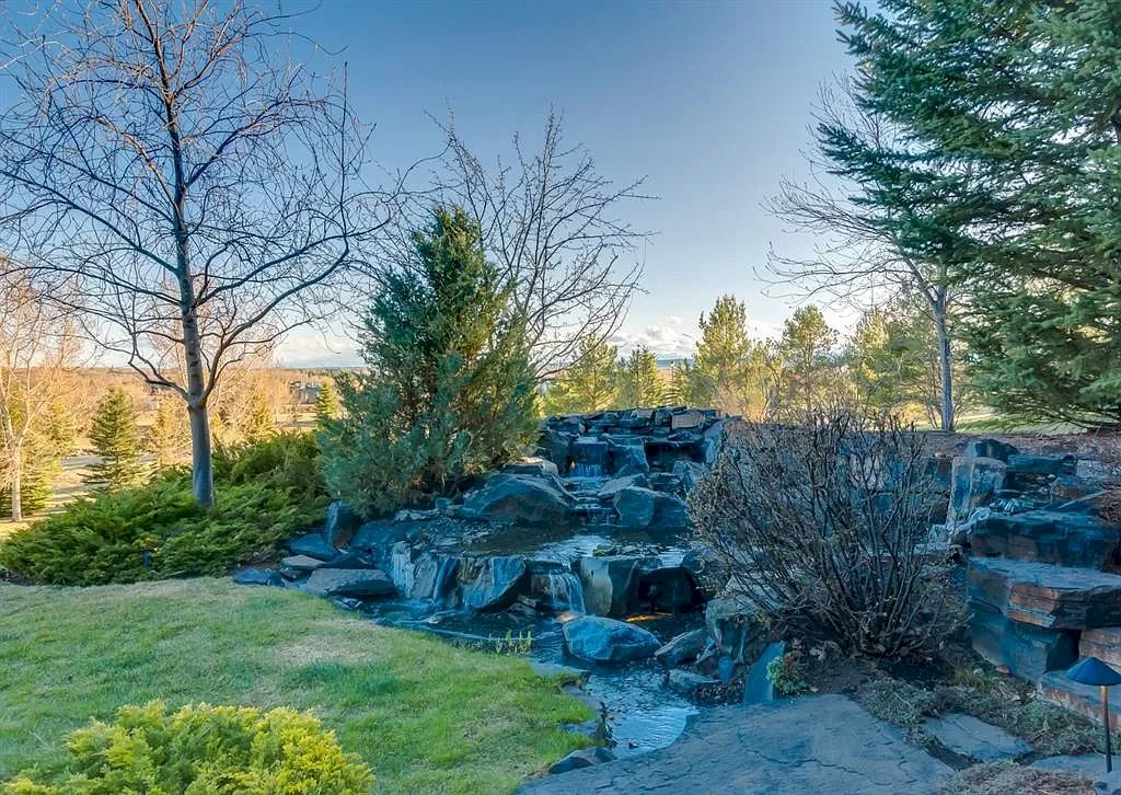 The Magnificent Home in Alberta features extensive hand-hewn grey Canmore limestone, soaring peaks, arched windows, and a majestic sloped roof now available for sale