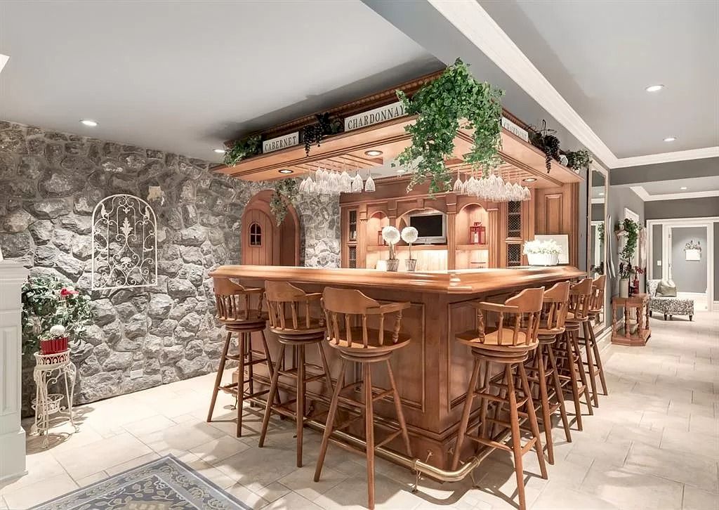 The Magnificent Home in Alberta features extensive hand-hewn grey Canmore limestone, soaring peaks, arched windows, and a majestic sloped roof now available for sale