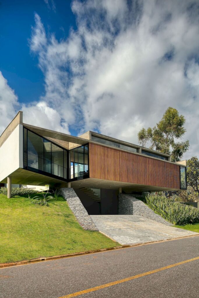 House 7 Patios, supported on slope with vegetation by TETRO Arquitetura