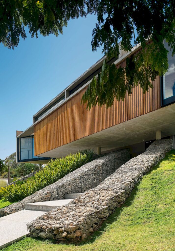 House 7 Patios, supported on slope with vegetation by TETRO Arquitetura