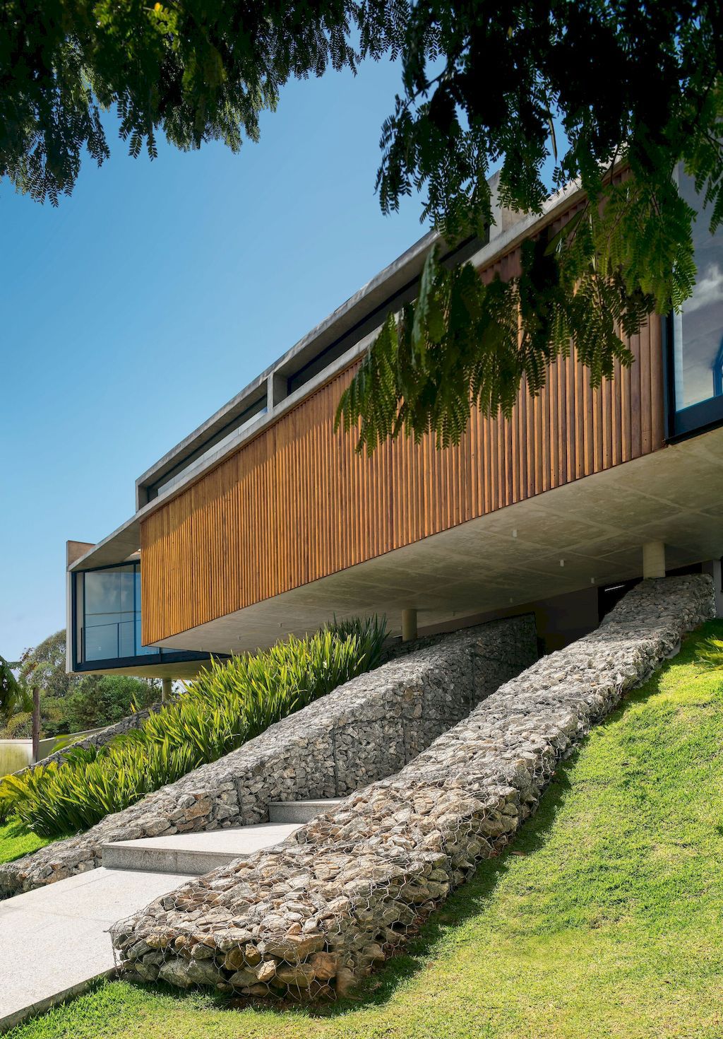 House 7 Patios, supported on slope with vegetation by TETRO Arquitetura