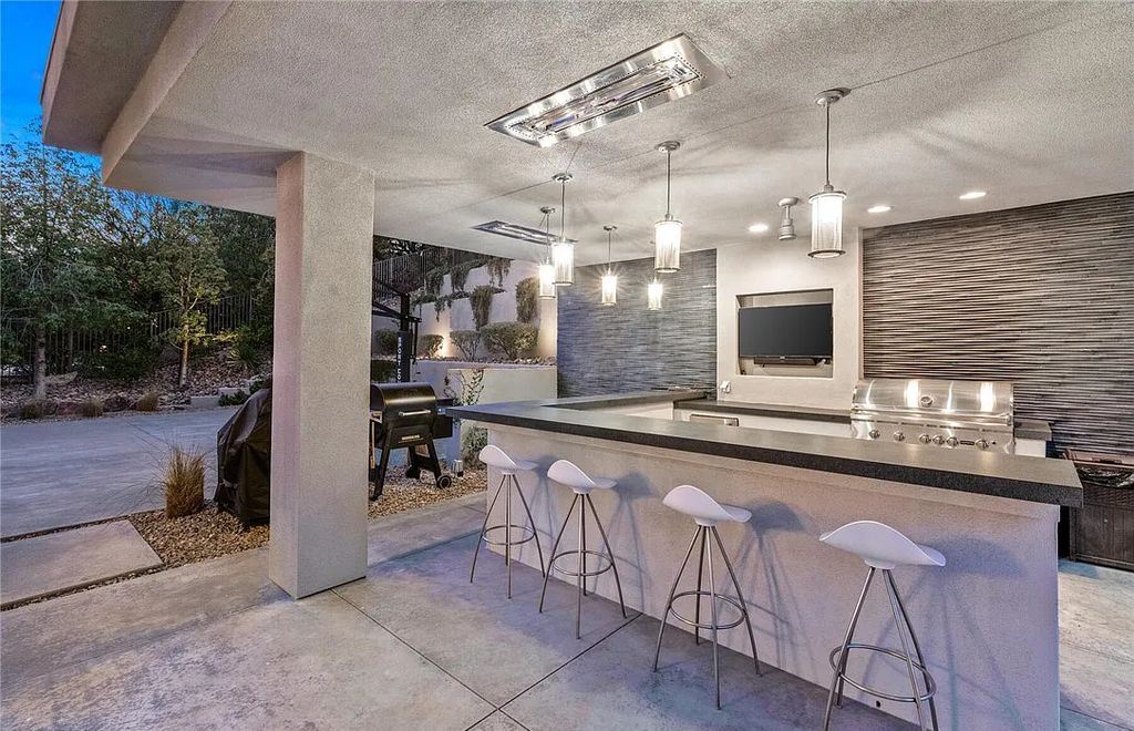 20 Skybird Court, Las Vegas, Nevada is a fully remodeled gem in the enclave of Redhawk behind the guard gates of The Ridges boasting a basketball area, pool with water slide and oversized wet deck, an indoor/outdoor bar, firepit, outdoor kitchen with ceiling mounted infrared heaters, and a wine cellar.