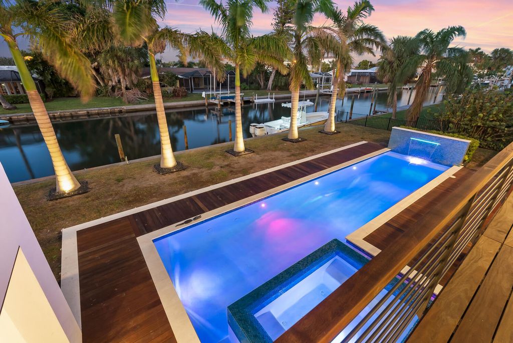 545 Kingfisher Lane, Longboat Key, Florida is a custom built modern canal front Longboat Key home with dramatic wide shell stone stair entrance, massive 60-inch ceramic tile flooring, 20-foot ceilings, skylights, lap-pool with 2 waterfall features, outdoor kitchen adjacent to indoor kitchen, and 5-car garage.