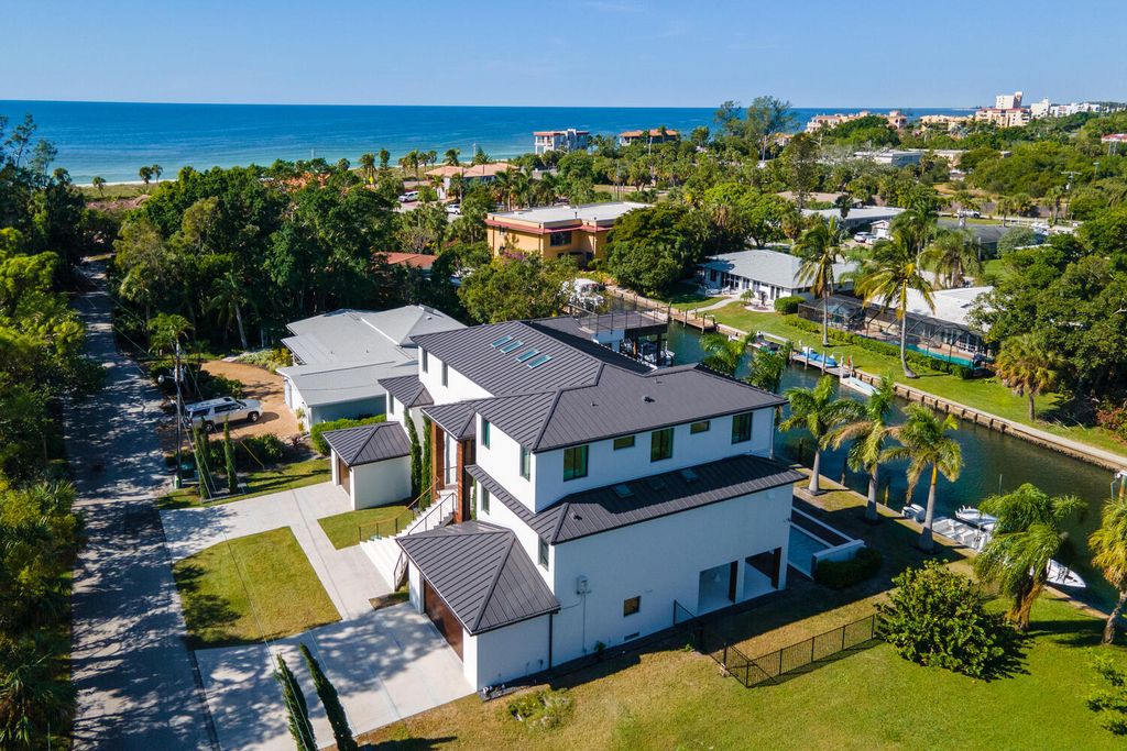 545 Kingfisher Lane, Longboat Key, Florida is a custom built modern canal front Longboat Key home with dramatic wide shell stone stair entrance, massive 60-inch ceramic tile flooring, 20-foot ceilings, skylights, lap-pool with 2 waterfall features, outdoor kitchen adjacent to indoor kitchen, and 5-car garage.