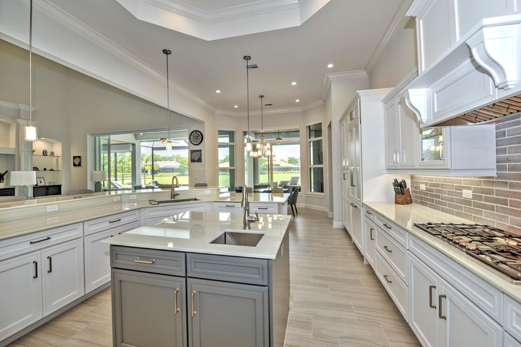 13335 Whispering Oaks Drive, Fort Myers, Florida is a custom built home by Royal Corinthian Homes in the highly sought-after luxury golf community Verandah with oversized tile throughout, custom cabinets including paneled refrigerator, thermidor appliance package, quartz kitchen countertops, interior mezzanine balcony, dual master suites.