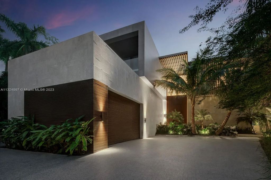 28 W Di Lido Drive, Miami Beach, Florida is stunning home where relaxed island living meets worldly sophistication, incredible features include 12ft ceilings, column-free living, 54ft of automated glass, media bookshelf, wine bar, & vapor fireplace highlight the textured travertine and white oak palette.