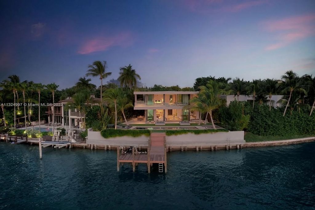 28 W Di Lido Drive, Miami Beach, Florida is stunning home where relaxed island living meets worldly sophistication, incredible features include 12ft ceilings, column-free living, 54ft of automated glass, media bookshelf, wine bar, & vapor fireplace highlight the textured travertine and white oak palette.