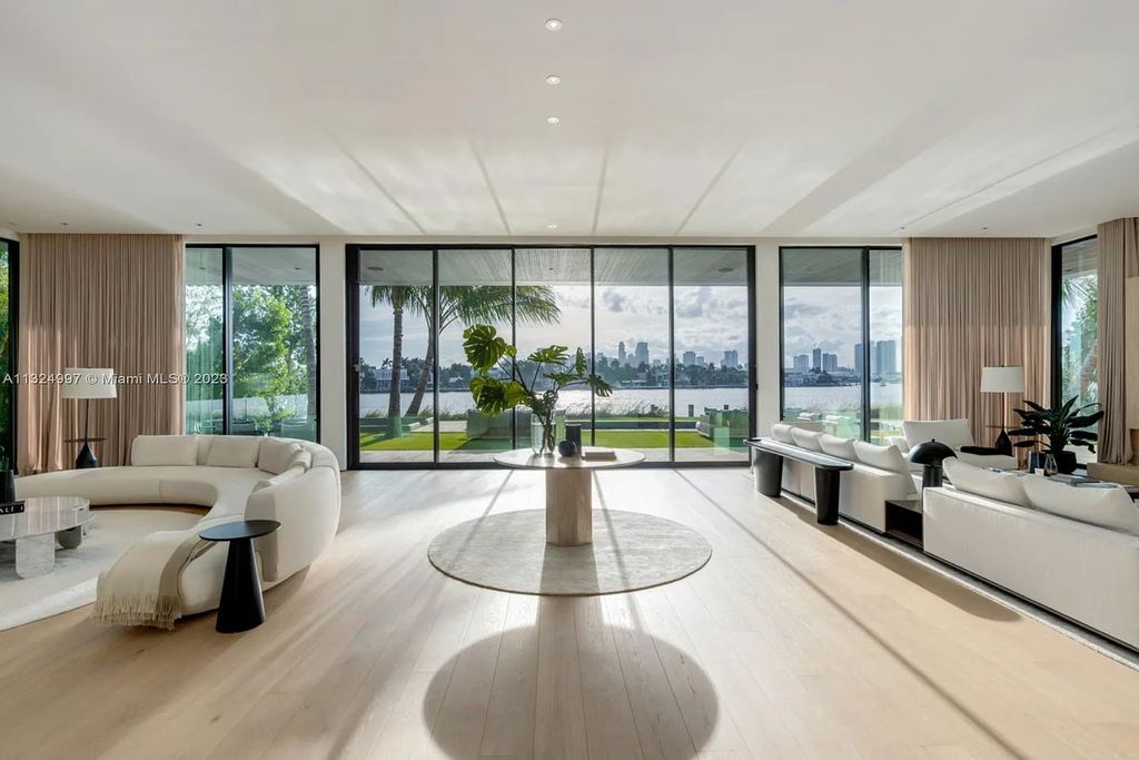 28 W Di Lido Drive, Miami Beach, Florida is stunning home where relaxed island living meets worldly sophistication, incredible features include 12ft ceilings, column-free living, 54ft of automated glass, media bookshelf, wine bar, & vapor fireplace highlight the textured travertine and white oak palette.