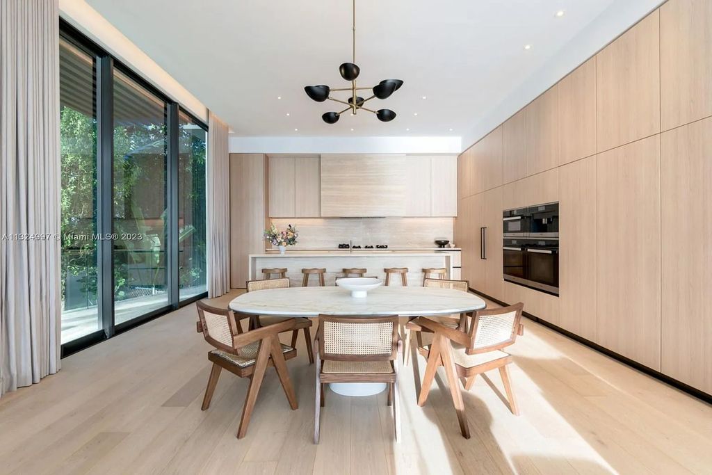 28 W Di Lido Drive, Miami Beach, Florida is stunning home where relaxed island living meets worldly sophistication, incredible features include 12ft ceilings, column-free living, 54ft of automated glass, media bookshelf, wine bar, & vapor fireplace highlight the textured travertine and white oak palette.