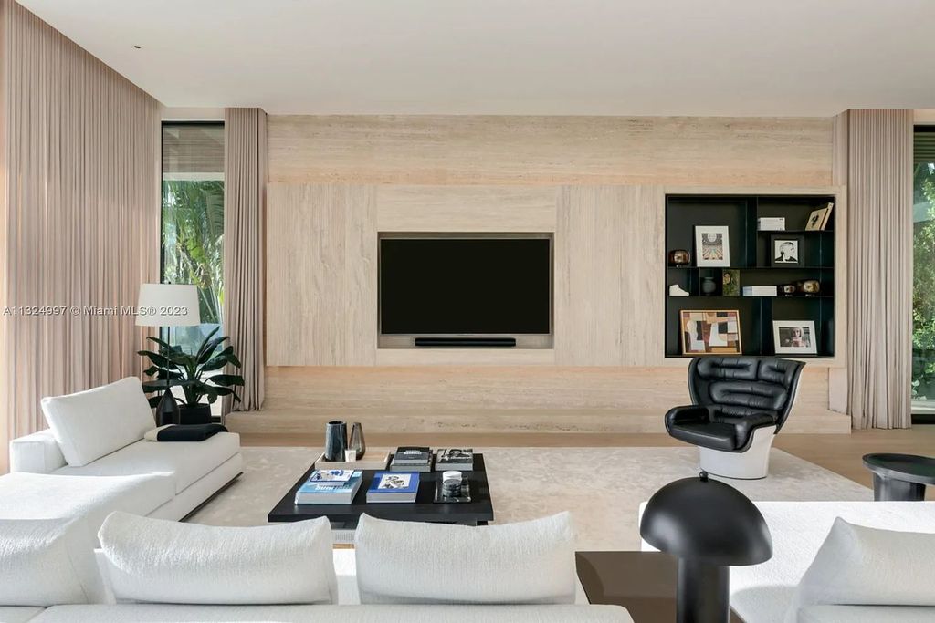 28 W Di Lido Drive, Miami Beach, Florida is stunning home where relaxed island living meets worldly sophistication, incredible features include 12ft ceilings, column-free living, 54ft of automated glass, media bookshelf, wine bar, & vapor fireplace highlight the textured travertine and white oak palette.