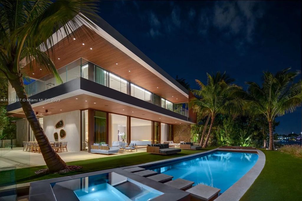 28 W Di Lido Drive, Miami Beach, Florida is stunning home where relaxed island living meets worldly sophistication, incredible features include 12ft ceilings, column-free living, 54ft of automated glass, media bookshelf, wine bar, & vapor fireplace highlight the textured travertine and white oak palette.
