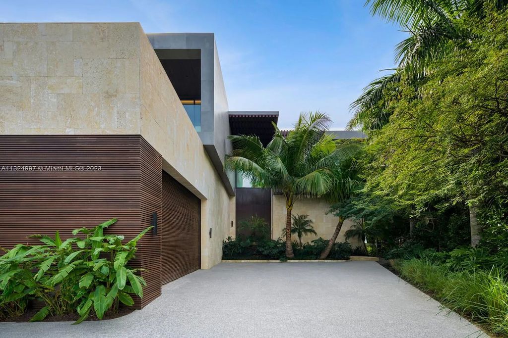 28 W Di Lido Drive, Miami Beach, Florida is stunning home where relaxed island living meets worldly sophistication, incredible features include 12ft ceilings, column-free living, 54ft of automated glass, media bookshelf, wine bar, & vapor fireplace highlight the textured travertine and white oak palette.