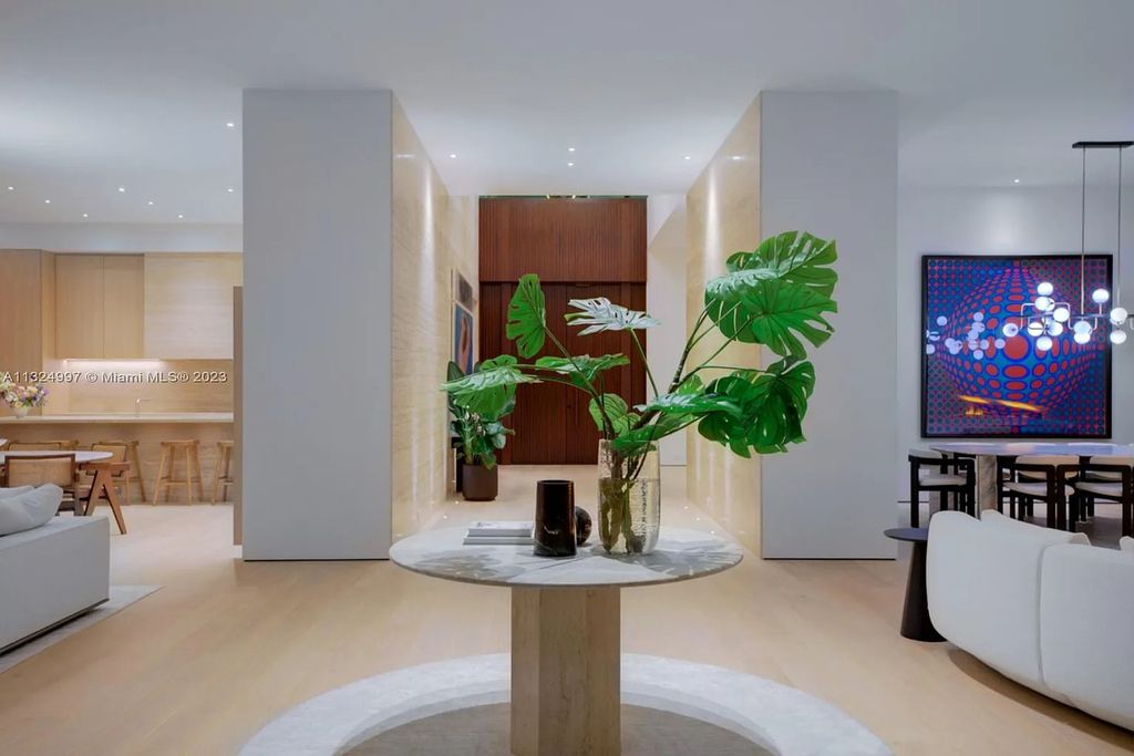28 W Di Lido Drive, Miami Beach, Florida is stunning home where relaxed island living meets worldly sophistication, incredible features include 12ft ceilings, column-free living, 54ft of automated glass, media bookshelf, wine bar, & vapor fireplace highlight the textured travertine and white oak palette.