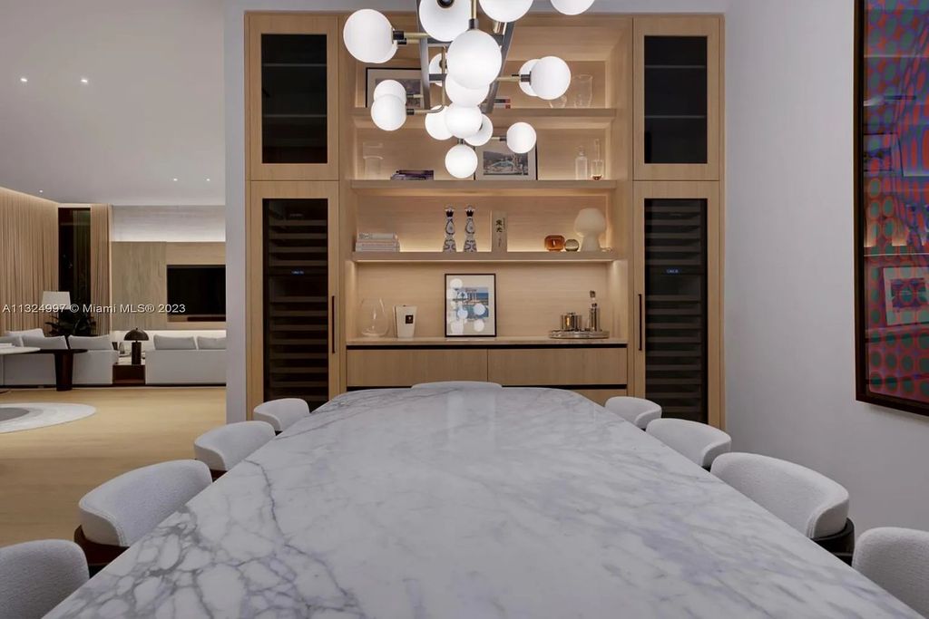28 W Di Lido Drive, Miami Beach, Florida is stunning home where relaxed island living meets worldly sophistication, incredible features include 12ft ceilings, column-free living, 54ft of automated glass, media bookshelf, wine bar, & vapor fireplace highlight the textured travertine and white oak palette.