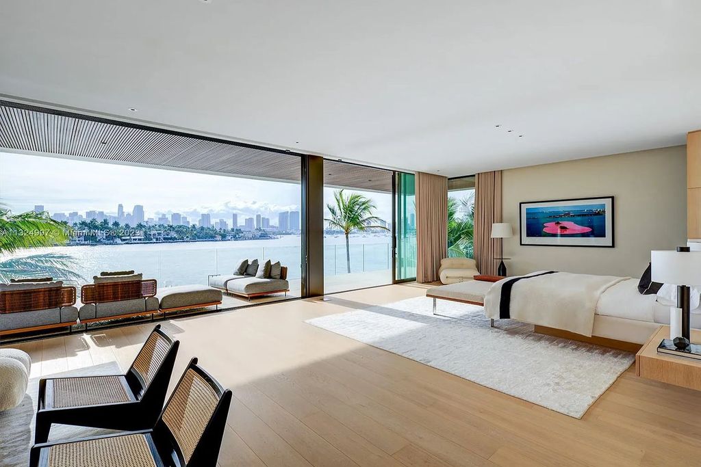 28 W Di Lido Drive, Miami Beach, Florida is stunning home where relaxed island living meets worldly sophistication, incredible features include 12ft ceilings, column-free living, 54ft of automated glass, media bookshelf, wine bar, & vapor fireplace highlight the textured travertine and white oak palette.
