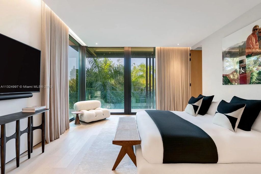 28 W Di Lido Drive, Miami Beach, Florida is stunning home where relaxed island living meets worldly sophistication, incredible features include 12ft ceilings, column-free living, 54ft of automated glass, media bookshelf, wine bar, & vapor fireplace highlight the textured travertine and white oak palette.