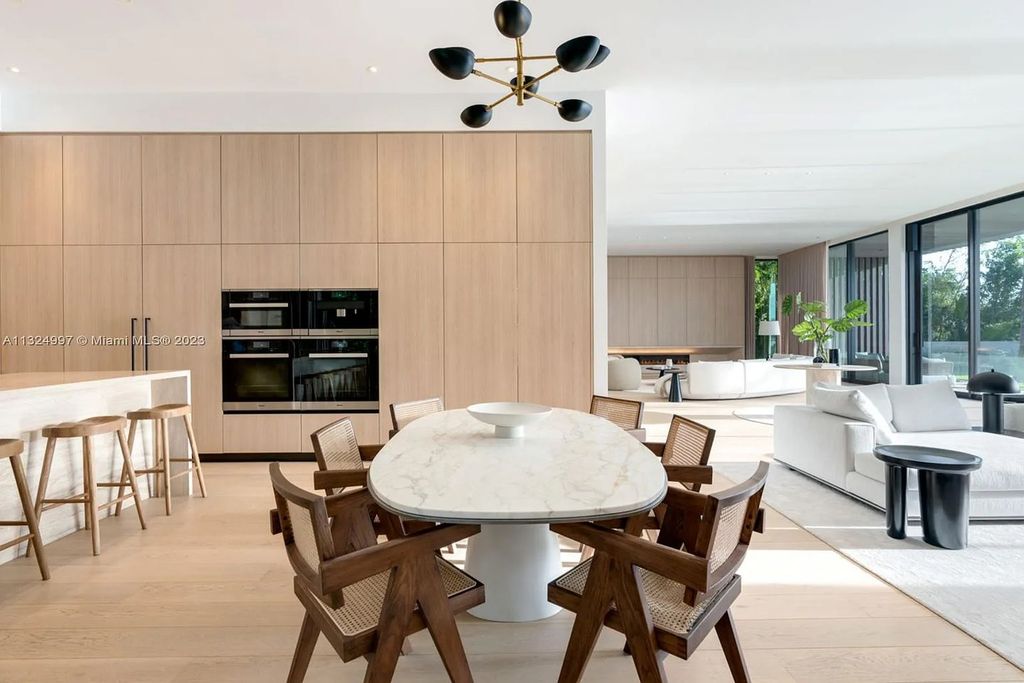 28 W Di Lido Drive, Miami Beach, Florida is stunning home where relaxed island living meets worldly sophistication, incredible features include 12ft ceilings, column-free living, 54ft of automated glass, media bookshelf, wine bar, & vapor fireplace highlight the textured travertine and white oak palette.