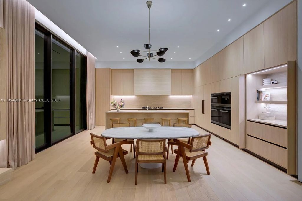 28 W Di Lido Drive, Miami Beach, Florida is stunning home where relaxed island living meets worldly sophistication, incredible features include 12ft ceilings, column-free living, 54ft of automated glass, media bookshelf, wine bar, & vapor fireplace highlight the textured travertine and white oak palette.