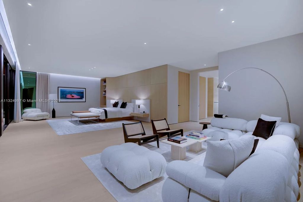 28 W Di Lido Drive, Miami Beach, Florida is stunning home where relaxed island living meets worldly sophistication, incredible features include 12ft ceilings, column-free living, 54ft of automated glass, media bookshelf, wine bar, & vapor fireplace highlight the textured travertine and white oak palette.