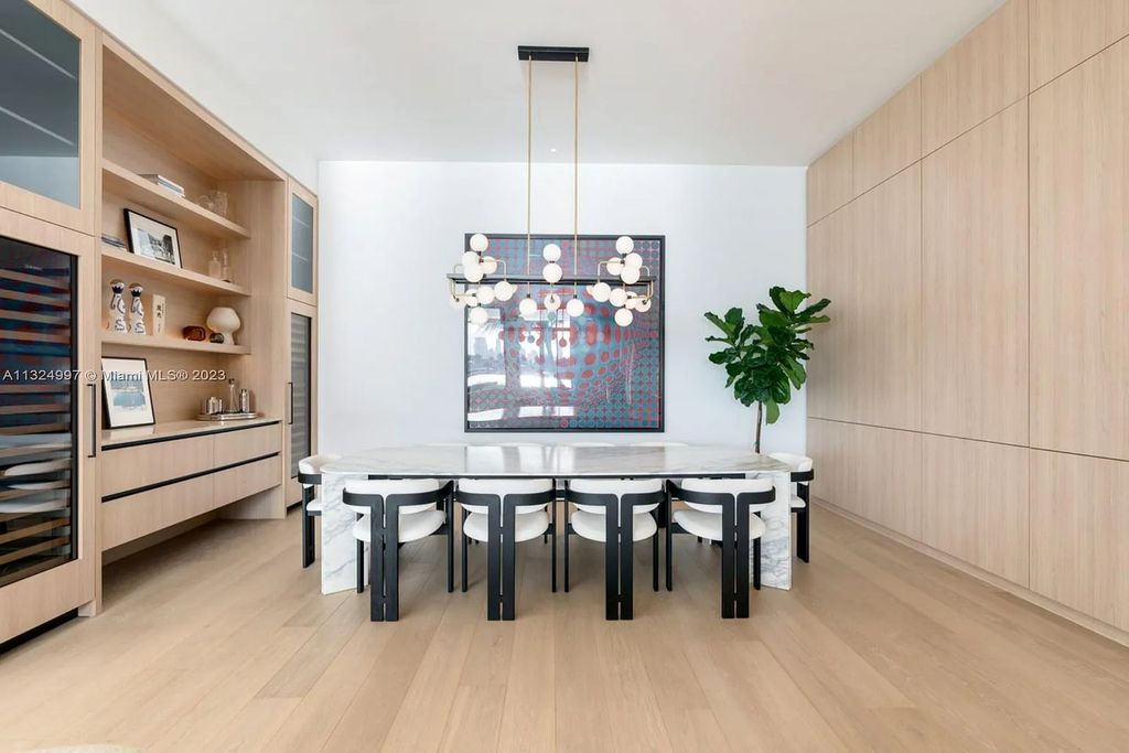 28 W Di Lido Drive, Miami Beach, Florida is stunning home where relaxed island living meets worldly sophistication, incredible features include 12ft ceilings, column-free living, 54ft of automated glass, media bookshelf, wine bar, & vapor fireplace highlight the textured travertine and white oak palette.
