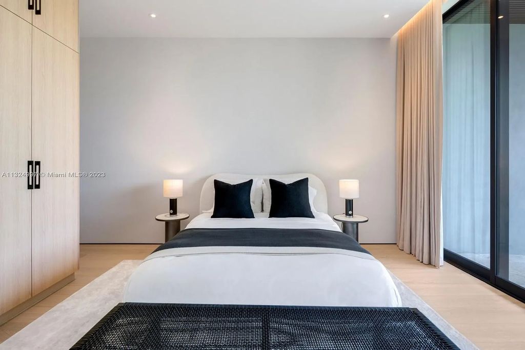 28 W Di Lido Drive, Miami Beach, Florida is stunning home where relaxed island living meets worldly sophistication, incredible features include 12ft ceilings, column-free living, 54ft of automated glass, media bookshelf, wine bar, & vapor fireplace highlight the textured travertine and white oak palette.
