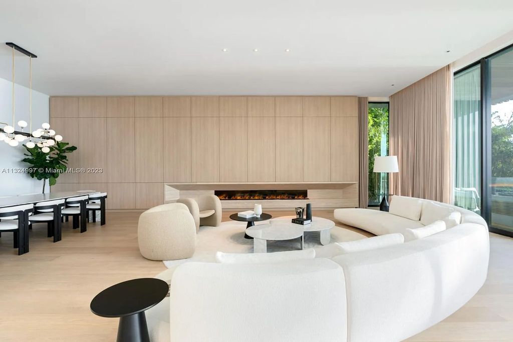 28 W Di Lido Drive, Miami Beach, Florida is stunning home where relaxed island living meets worldly sophistication, incredible features include 12ft ceilings, column-free living, 54ft of automated glass, media bookshelf, wine bar, & vapor fireplace highlight the textured travertine and white oak palette.