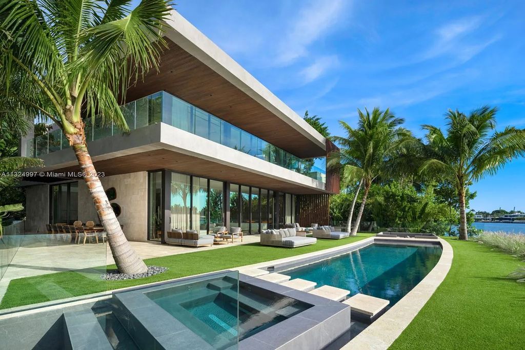 28 W Di Lido Drive, Miami Beach, Florida is stunning home where relaxed island living meets worldly sophistication, incredible features include 12ft ceilings, column-free living, 54ft of automated glass, media bookshelf, wine bar, & vapor fireplace highlight the textured travertine and white oak palette.