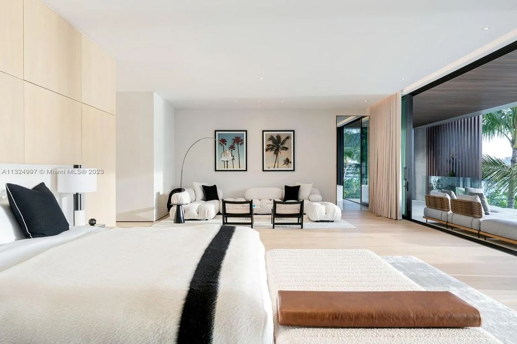 28 W Di Lido Drive, Miami Beach, Florida is stunning home where relaxed island living meets worldly sophistication, incredible features include 12ft ceilings, column-free living, 54ft of automated glass, media bookshelf, wine bar, & vapor fireplace highlight the textured travertine and white oak palette.