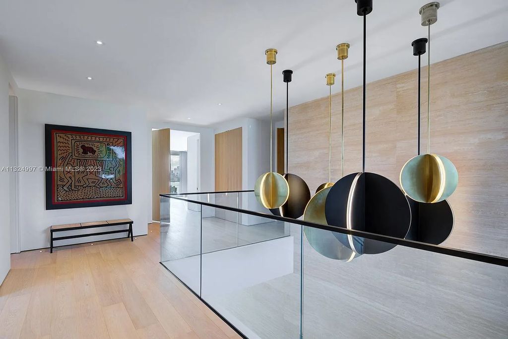 28 W Di Lido Drive, Miami Beach, Florida is stunning home where relaxed island living meets worldly sophistication, incredible features include 12ft ceilings, column-free living, 54ft of automated glass, media bookshelf, wine bar, & vapor fireplace highlight the textured travertine and white oak palette.