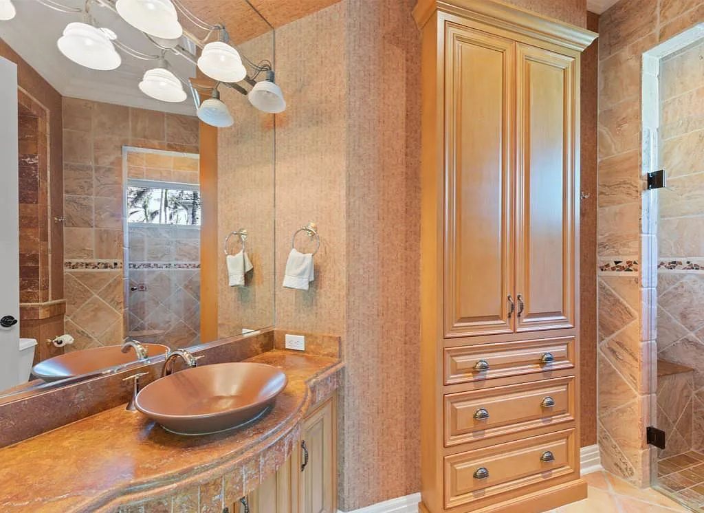 26079 Fawnwood Court, Bonita Springs, Florida, is a beautiful lakefront home built on a prominent corner lot in desirable Spring Ridge. With warm and inviting décor and a separate waterfall flowing into a tropical lagoon pool, it is a timeless design.
