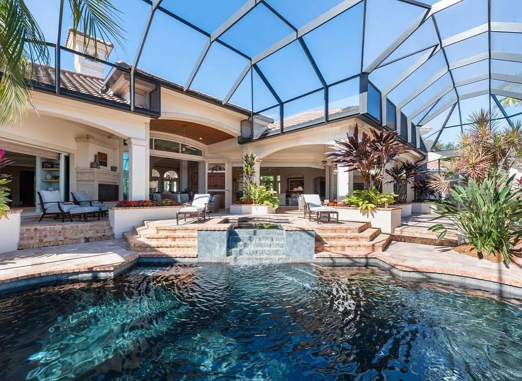 26079 Fawnwood Court, Bonita Springs, Florida, is a beautiful lakefront home built on a prominent corner lot in desirable Spring Ridge. With warm and inviting décor and a separate waterfall flowing into a tropical lagoon pool, it is a timeless design.