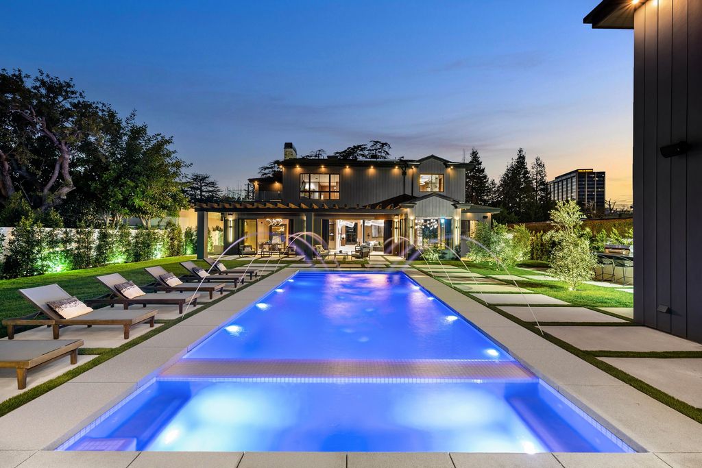 The recently built gated estate at 4508 Haskell Ave in Encino's prestigious Royal Oaks community is a true masterpiece of luxury and design. Upon entering the property, guests are welcomed by an impressive wide entry hallway with ultra-high ceilings and European oak floors. The hallway leads to the stunning living room with stone entertainment bars and a formal dining room with a fireplace and private patio.