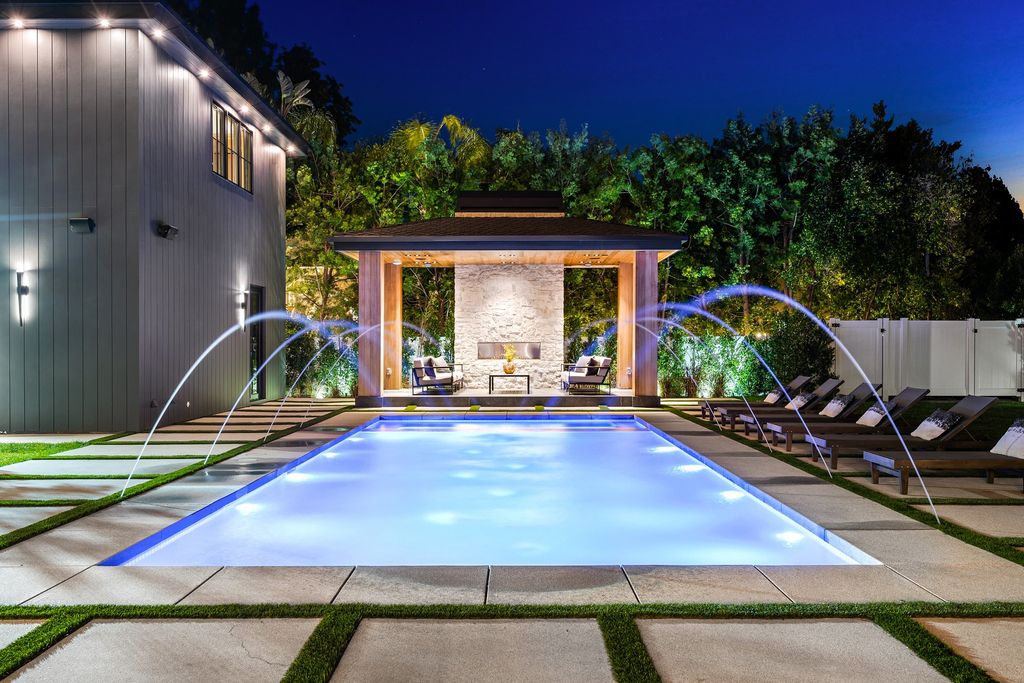 The recently built gated estate at 4508 Haskell Ave in Encino's prestigious Royal Oaks community is a true masterpiece of luxury and design. Upon entering the property, guests are welcomed by an impressive wide entry hallway with ultra-high ceilings and European oak floors. The hallway leads to the stunning living room with stone entertainment bars and a formal dining room with a fireplace and private patio.