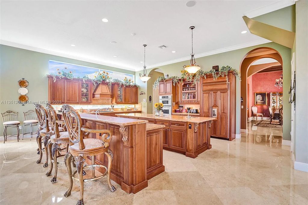 3308 Islewood Avenue, Weston, Florida is located in the prestigious gated community of Windmill Reserve, and it offers luxurious living on a grand scale. Situated on a premium lake lot with a lushly landscaped yard, this home in Weston features a gas-heated pool/spa, covered summer kitchen, Chicago brick patio, and roll-down shades, making it perfect for entertaining guests or enjoying time with family.