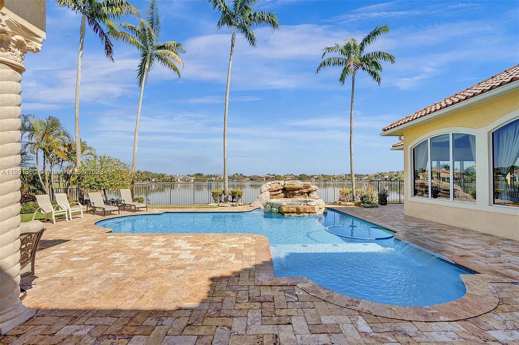 3308 Islewood Avenue, Weston, Florida is located in the prestigious gated community of Windmill Reserve, and it offers luxurious living on a grand scale. Situated on a premium lake lot with a lushly landscaped yard, this home in Weston features a gas-heated pool/spa, covered summer kitchen, Chicago brick patio, and roll-down shades, making it perfect for entertaining guests or enjoying time with family.