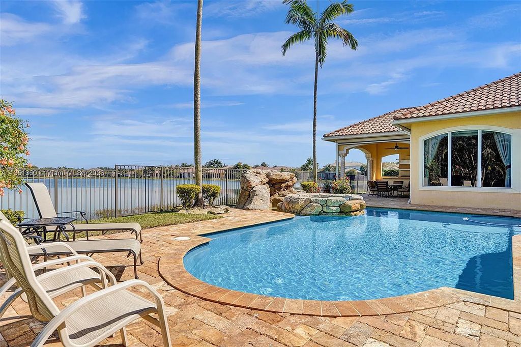 3308 Islewood Avenue, Weston, Florida is located in the prestigious gated community of Windmill Reserve, and it offers luxurious living on a grand scale. Situated on a premium lake lot with a lushly landscaped yard, this home in Weston features a gas-heated pool/spa, covered summer kitchen, Chicago brick patio, and roll-down shades, making it perfect for entertaining guests or enjoying time with family.