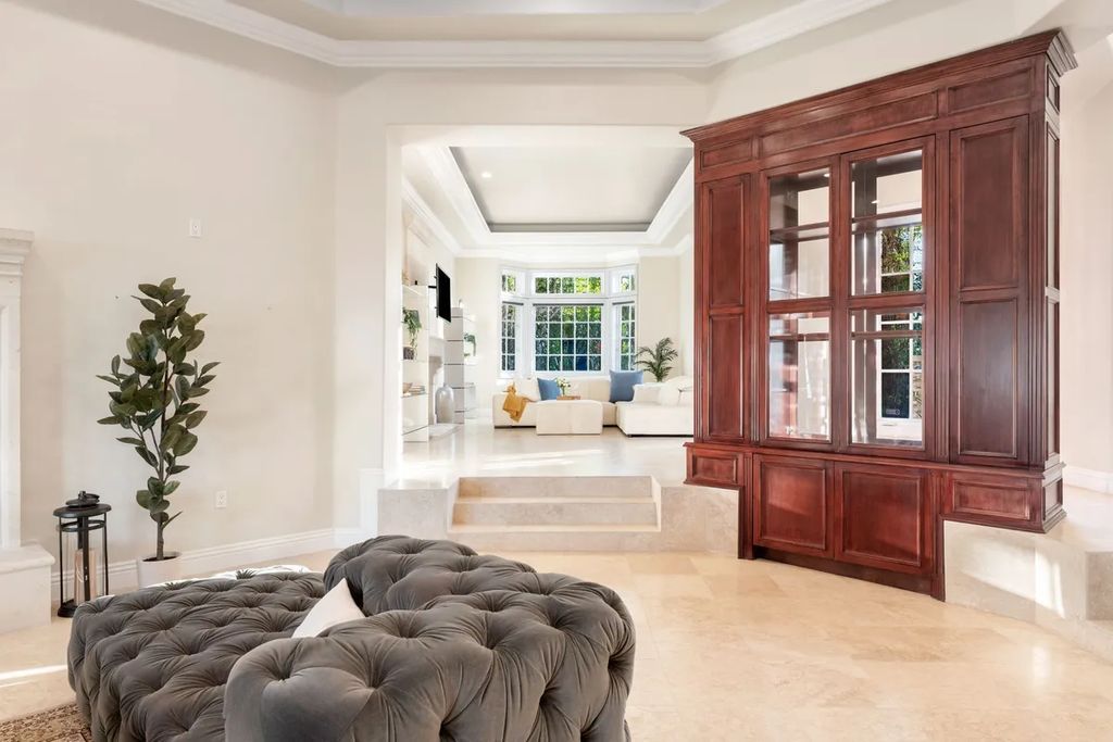 This exquisite estate offers breathtaking 360-degree views of the ocean sunsets, city lights, and Santa Monica mountains skyline, visible from its three stunning balconies. With over 9,300 square feet of space, this luxurious property boasts five bedrooms, seven bathrooms, three living rooms, formal and informal dining areas, and five beautiful fireplaces. The grand entrance through double doors leads to a dramatic 2-story foyer with 30-foot windows that flood the space with natural light, and limestone floors create an elegant touch.