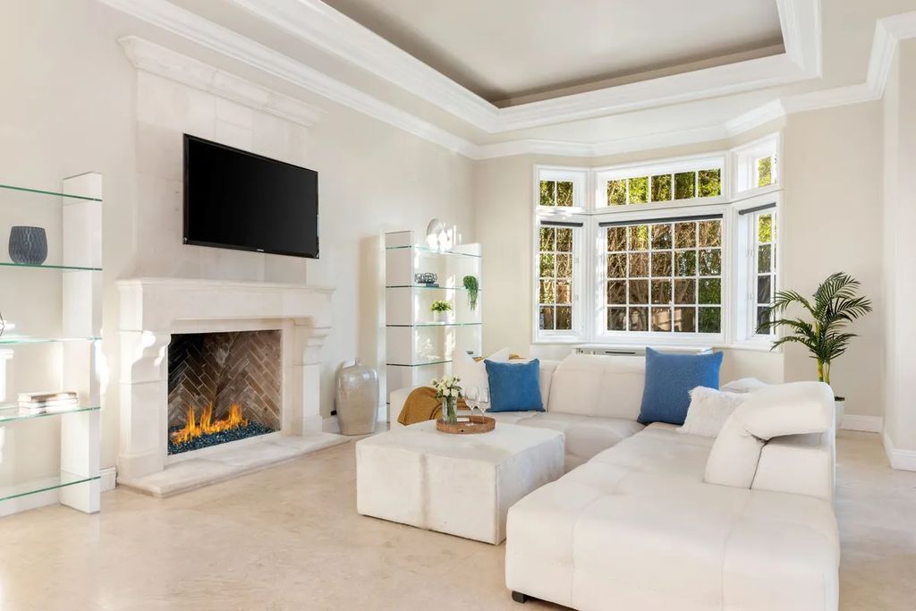 This exquisite estate offers breathtaking 360-degree views of the ocean sunsets, city lights, and Santa Monica mountains skyline, visible from its three stunning balconies. With over 9,300 square feet of space, this luxurious property boasts five bedrooms, seven bathrooms, three living rooms, formal and informal dining areas, and five beautiful fireplaces. The grand entrance through double doors leads to a dramatic 2-story foyer with 30-foot windows that flood the space with natural light, and limestone floors create an elegant touch.