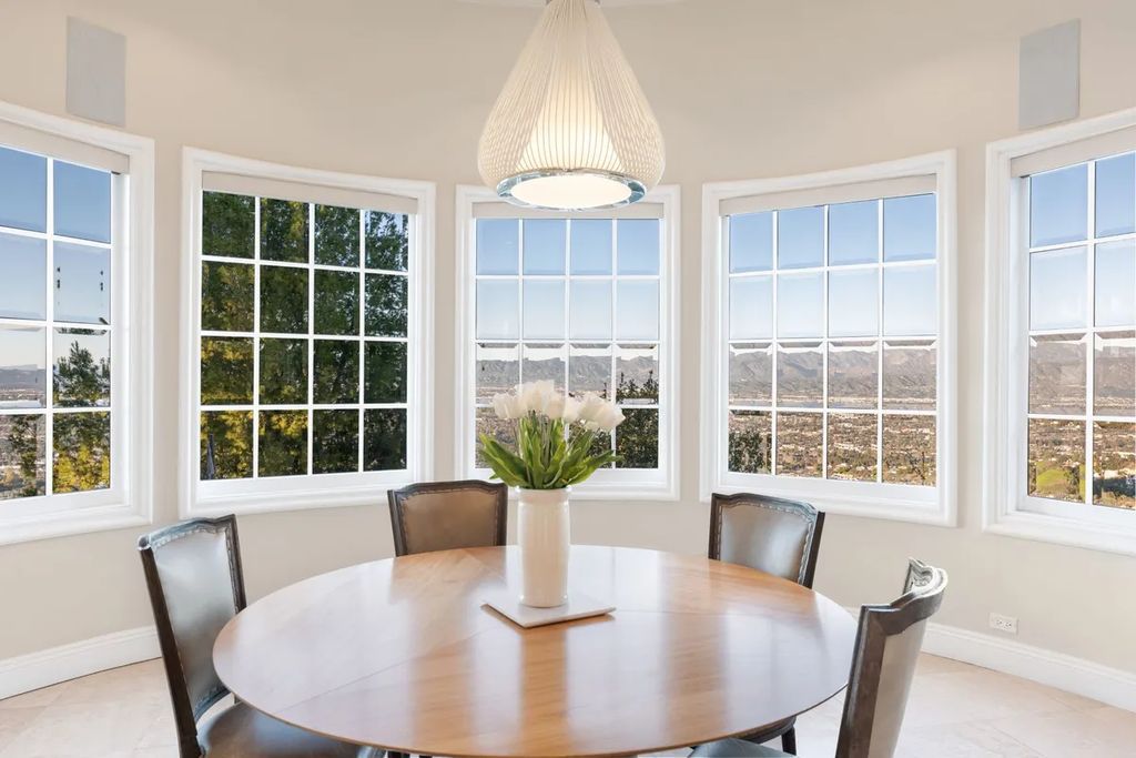 This exquisite estate offers breathtaking 360-degree views of the ocean sunsets, city lights, and Santa Monica mountains skyline, visible from its three stunning balconies. With over 9,300 square feet of space, this luxurious property boasts five bedrooms, seven bathrooms, three living rooms, formal and informal dining areas, and five beautiful fireplaces. The grand entrance through double doors leads to a dramatic 2-story foyer with 30-foot windows that flood the space with natural light, and limestone floors create an elegant touch.